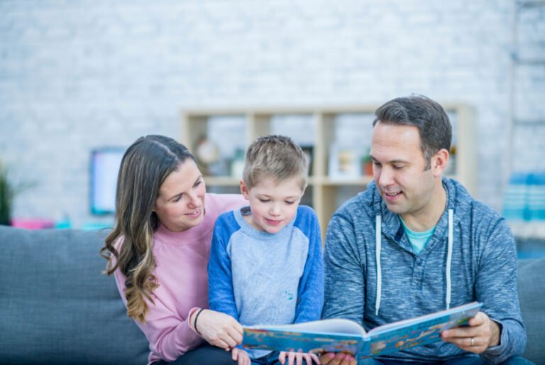 Kanepede çocuklarıyla birlikte kitap okuyan anne ve baba
